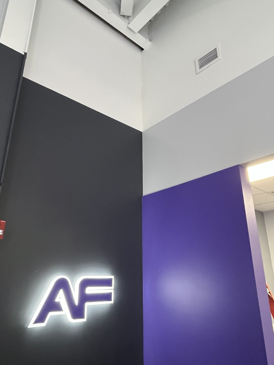 Commercial gym interior featuring multiple painted colors and illuminated AF sign